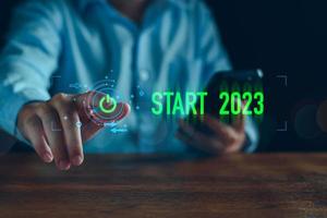 homme d'affaires touchant le bouton de démarrage de l'écran virtuel pour la nouvelle année 2023, commencez la nouvelle année 2023 avec un plan d'objectifs, un concept d'objectif, un plan d'action, une stratégie, une vision d'entreprise du nouvel an. nouvelle entreprise en démarrage. photo