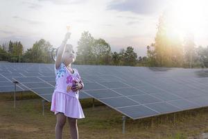 main de fille tenant une ampoule lumineuse à la ferme solaire montrant une stratégie commerciale créative avec ampoule comme concept. photo