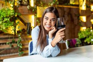 image de jolie jolie jeune femme assise dans un café tenant un verre et buvant du vin. portrait d'une belle femme touristique de dégustation de vins. photo