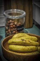 un bol de bananes mûres et un pot de noisettes dans la cuisine prêt pour un petit déjeuner sain photo