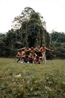 un groupe d'indonésiens dansant pose dans un costume doré tout en se maquillant sur l'herbe verte photo