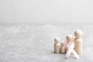 figurine en bois familiale et ruban rose. concept de traitement du cancer. photo