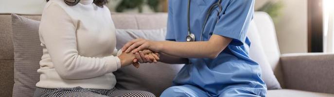 un patient heureux tient le soignant pour une main tout en passant du temps ensemble. femme âgée en maison de retraite et infirmière. photo