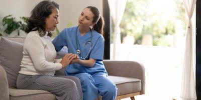 un patient heureux tient le soignant pour une main tout en passant du temps ensemble. femme âgée en maison de retraite et infirmière. photo