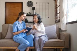 infirmière asiatique montrant un rapport de bilan de santé à grand-mère et donnant des conseils. la vie assistée médicale rend visite à un patient âgé à domicile. concept de soins infirmiers à domicile et de soignant photo