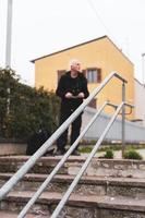 homme mûr chanteur de rap posant dans des escaliers à l'extérieur à la périphérie d'une ville photo