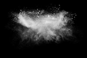 nuage d'explosion de poudre blanche sur fond noir. éclaboussures de particules de poussière blanche. photo