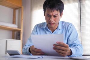 les hommes d'affaires s'inquiètent des documents ou des factures qu'ils tiennent entre leurs mains. stressé par le poids des dépenses domestiques photo