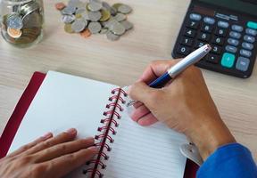 une photo d'un homme d'affaires prenant des notes et utilisant une calculatrice pour calculer le revenu du ménage