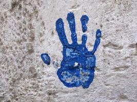empreinte de main colorée bleue sur mur blanc photo
