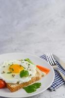 un œuf frit sur du pain grillé garni de graines de poivre avec des carottes et des oignons nouveaux
