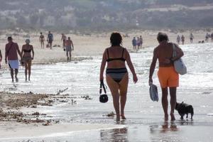 plage solitaire avec des gens se promenant sur le sable au bord des vagues de la mer photo