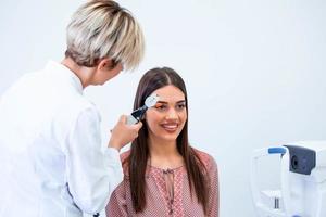 vérification de la santé oculaire avec équipement ophtalmologique en laboratoire. à l'aide d'un oculiste d'appareil spécial essayant d'améliorer la vision d'une jeune jolie fille. travailler avec des dispositifs médicaux pour la santé oculaire. photo