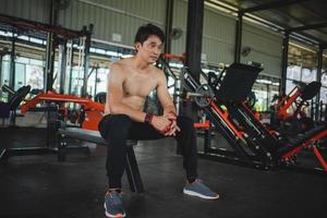 jeunes hommes se reposant après un entraînement intensif dans la salle de gym. fitness homme en bonne santé fatigué après un exercice de musculation au gymnase. photo