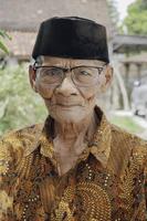 un portrait d'un vieil homme asiatique portant une chemise et des lunettes de batik photo