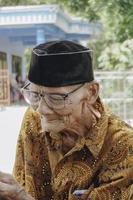 un portrait d'un vieil homme asiatique portant une chemise et des lunettes de batik photo