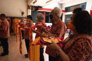 ville de bandung, indonésie, 2022 - le vieil homme apporte les offrandes à l'autel en priant avec les moines photo