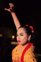 le beau visage en gros plan d'une femme javanaise maquillée lors d'un spectacle de danse traditionnelle tout en portant un costume jaune photo