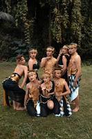 un groupe d'asiatiques s'amusant en prenant une séance photo avec un costume de danse doré devant la jungle