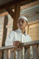 un musulman debout sur le balcon d'une maison en bois du village photo