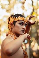 visages en colère d'un homme asiatique avec une couronne dorée sur la tête tout en torse nu et en faisant poser les mains photo