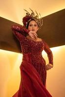femme asiatique en robe rouge posant avec une couronne d'or sur la tête photo