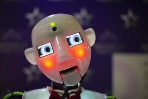 drôle de visage de robot éclairé par une lumière orange sur fond bleu. photo