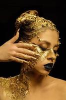 art de la mode peau dorée. fille modèle avec maquillage professionnel brillant glamour doré festif. bijoux en or, bijouterie, accessoires. beau corps métallique doré, lèvres et peau noires. photo
