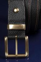 ceinture en cuir noir sur fond bleu foncé. photo