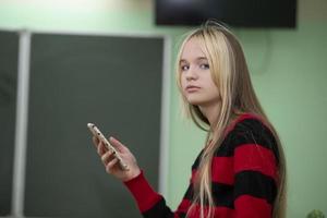adolescent d'âge scolaire secondaire. une adolescente se tient devant un tableau noir. photo