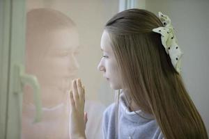 une adolescente triste regarde par la fenêtre, se sent seule. une fille réfléchie n'est pas satisfaite du problème. concept d'adolescence difficile. photo
