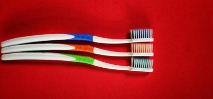 trois brosses à dents isolées sur fond rouge photo