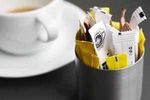 Sachet d'édulcorant substitut de sucre et tasse de thé sur fond blanc photo