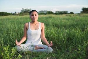 Yoga femme dans la posture du lotus dans un pré ensoleillé photo