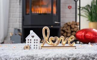 clé de la maison avec porte-clés sur fond de poêle cheminée avec feu et bois de chauffage dans un décor de saint valentin, love home. déménagement dans une nouvelle maison, hypothèque, location et achat immobilier photo