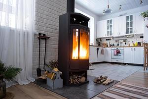 poêle noir, cheminée à l'intérieur de la maison de style loft. chauffage alternatif respectueux de l'environnement, pièce chaleureuse et confortable à la maison, combustion du bois photo