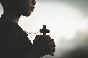 mains de garçon tenant une sainte croix et priant dieu, enfant priant pour la religion de dieu. photo