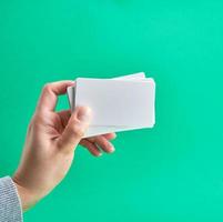 carte de visite en papier blanc dans une main féminine sur fond vert photo