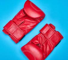 Paire de gants de boxe en cuir rouge sur fond bleu photo