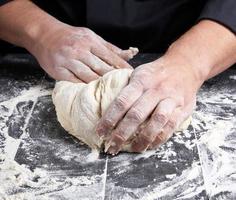 boulanger pétrit la pâte de farine de blé blanc photo