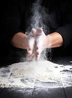 les mains de l'homme et les éclaboussures de farine de blé blanc photo