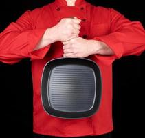 cuisinier en uniforme rouge tenant une poêle à frire noire carrée vide photo