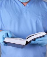 médecin en uniforme bleu tient un livre ouvert dans ses mains photo