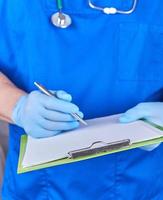 médecin en uniforme bleu tient un stylo et un porte-papier photo