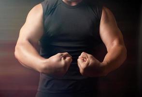 homme adulte avec une figure sportive en vêtements noirs a tendu ses muscles dans ses bras photo