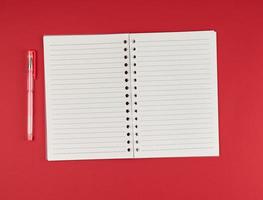 cahier ouvert en ligne et stylo gel sur fond rouge photo