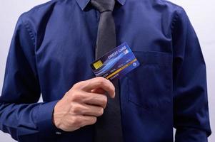 homme portant une chemise bleue tenant une carte de crédit bleue photo