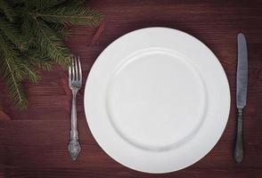 assiette vide blanche avec couteau et fourchette sur une surface en bois marron photo