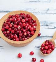 baies de canneberges rouges mûres dans une assiette en bois photo