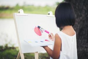 petite fille artiste peignant une image dans le parc photo